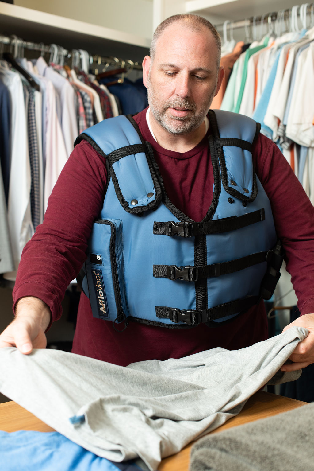 man wearing an afflovest and folding laundry